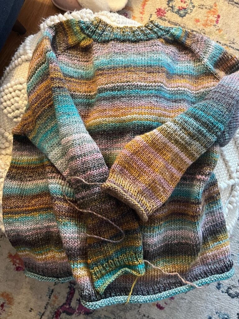 Finished raglan sweater laying on ottoman.